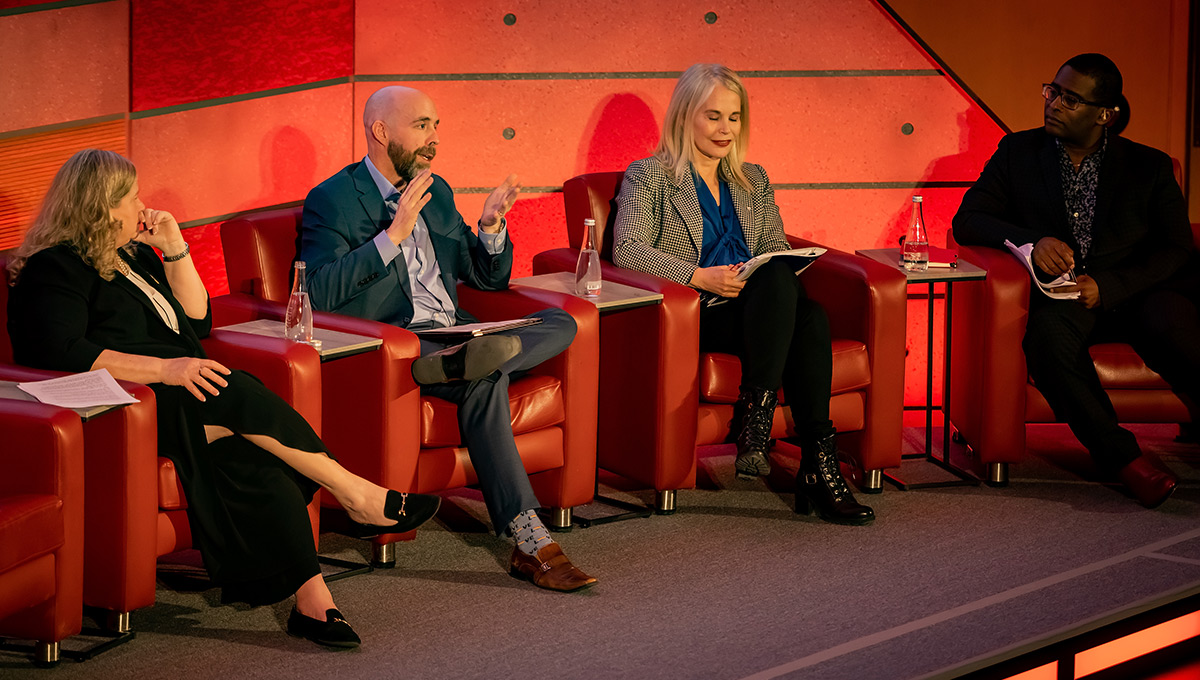 A man speaks on a stage during a panel discussion