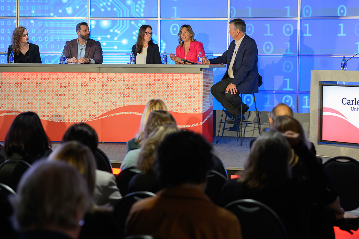 A panel of speakers with audience in the foreground.