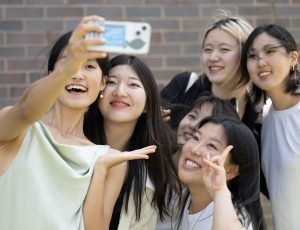 A group of friends take a photo outside the Athletics building