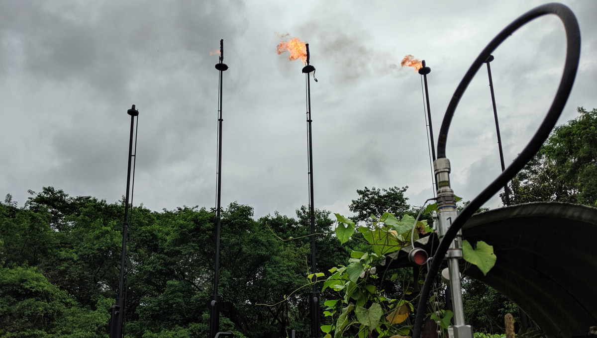 Gas flares giving of flame and smoke surrounded by rainforest in the Amazon.