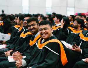 Seated students smile at a convocation ceremony.