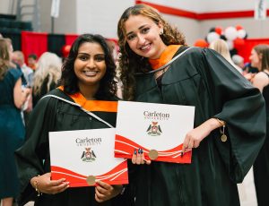 Two graduating students pose with their degrees .