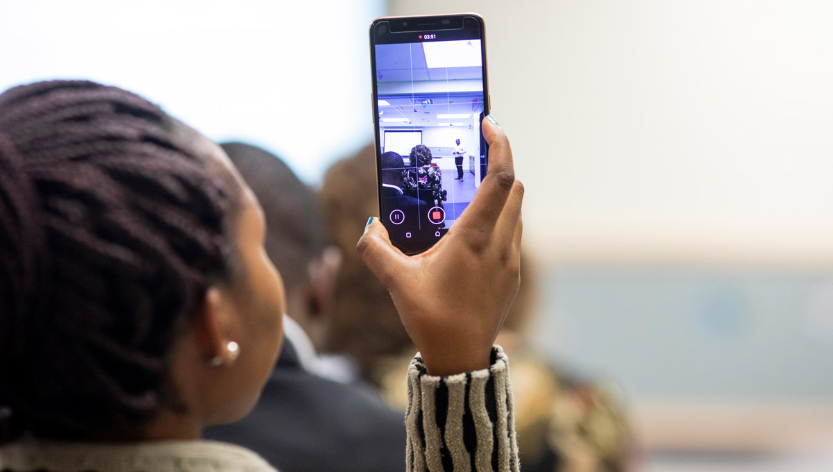 An attendee takes a picture of a speaker with her phone during the Carleton Climate Conversations.