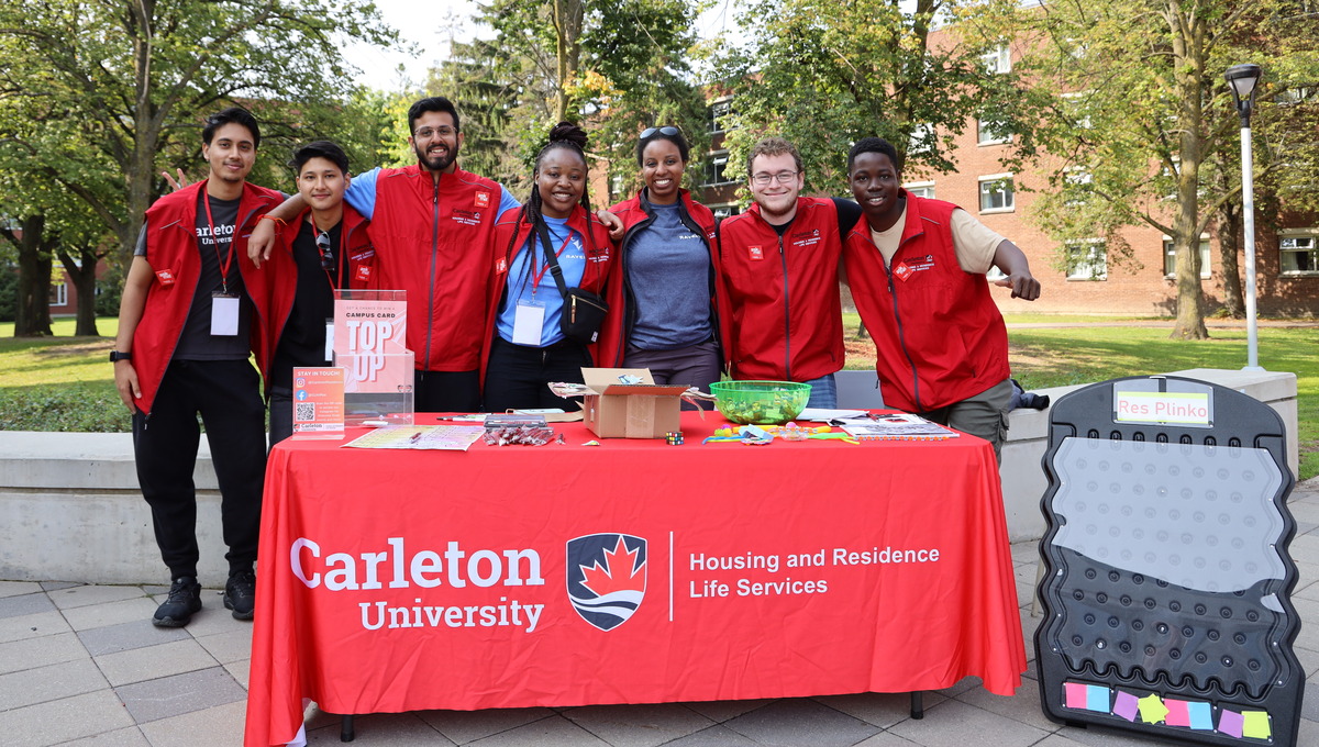 Group of students and staff standing at a welcome desk