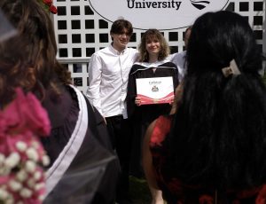 A recent graduate poses with supporters outside the Athletics Building.