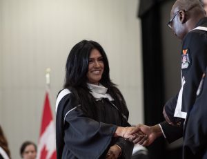 A graduating student shakes University President Tettey's hand as she crosses the stage.