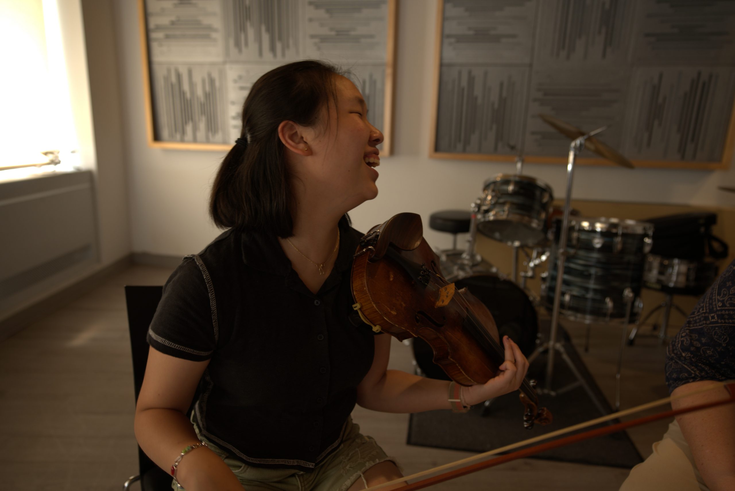 A woman with black hair and a black shirt playing violin