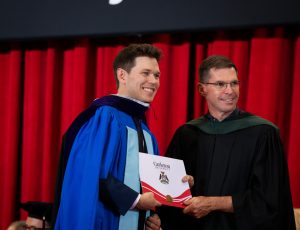 A graduating student receives his degree as he crosses the stage.