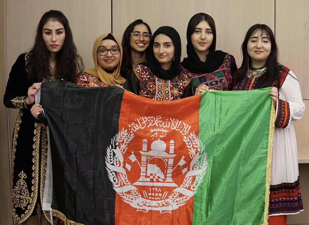 Six Afghani women hold up the Afghanistan flag