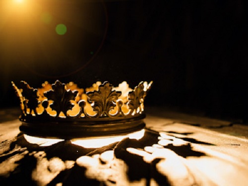An image of a golden crown, light from behind the crown casts a shadow.