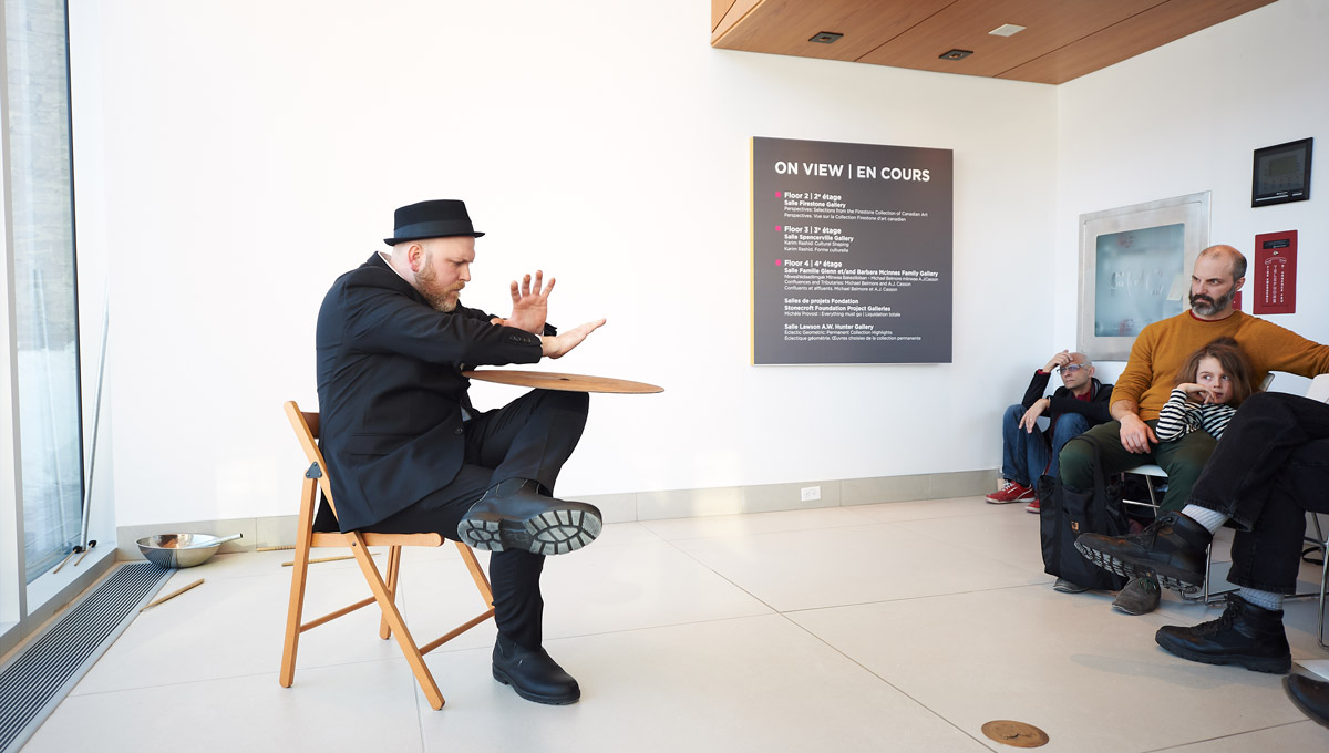 Jesse Stewart performs using a drum cymbal in front of an audience at the Ottawa Art Gallery.