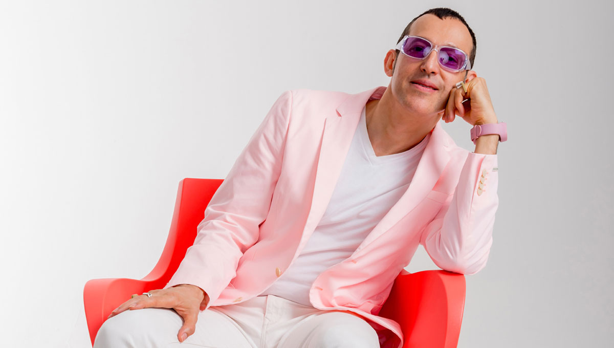 Karim Rashid sits in a red chair of his own design.