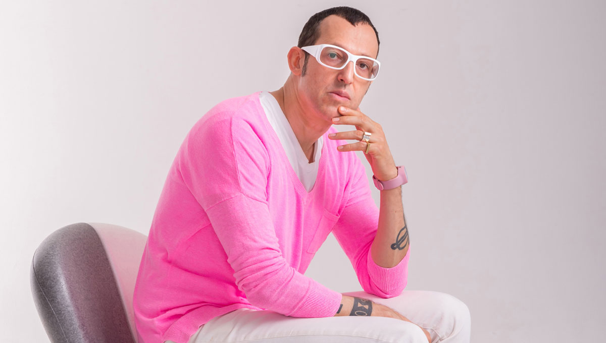 Karim Rashid sits in a two-toned chair of his own design.