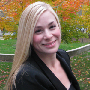 Blonde woman posing infront of a tree in fall with leaves changing colours