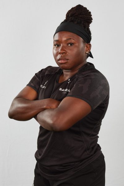Lauryn Walker stands with her arms crossed facing the camera, wearing a black collared Carleton Ravens shirt.