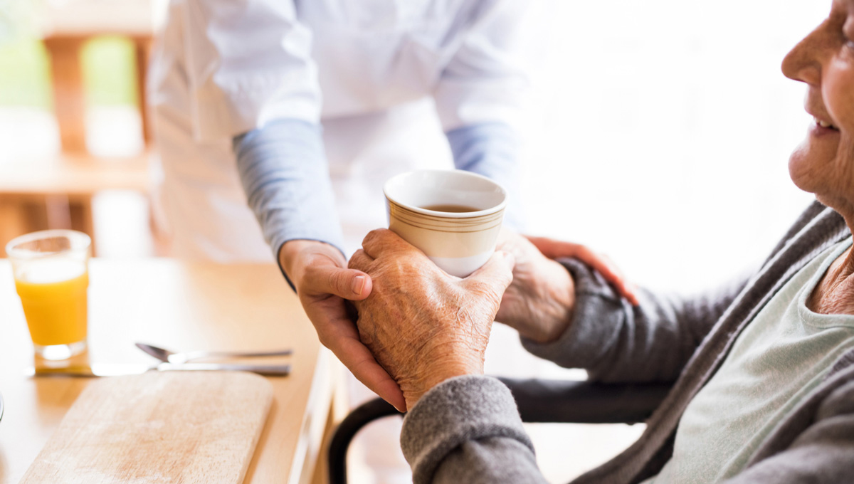 A retirement home worker helps an elderly resident.