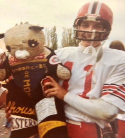 A man in a football uniform holds a stuffed bear