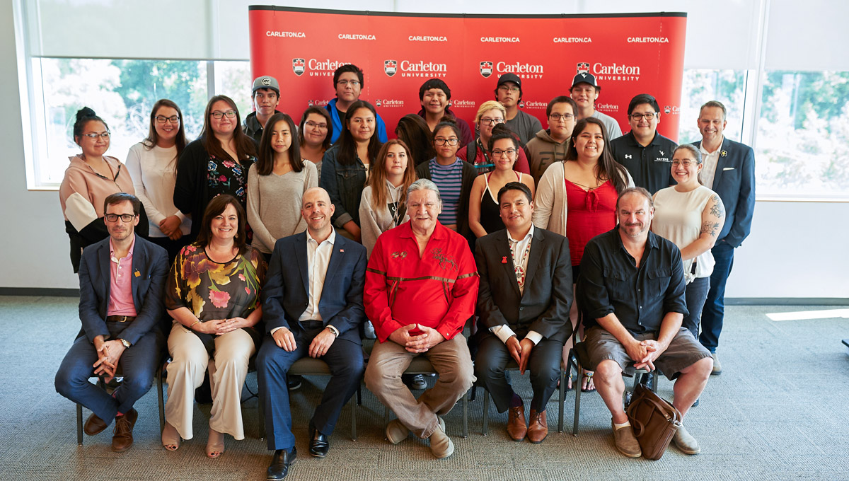 A group of youth from the Youth of Nishnawbe Aski Nation poses together with Carleton and NAN representatives in Richcraft Hall.