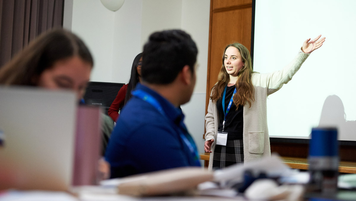 Nicole Adebar raises her hand for emphasis while speaking to an audience.