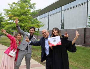 A Carleton graduate and her family pose for the camera while holding up peace signs with their hands