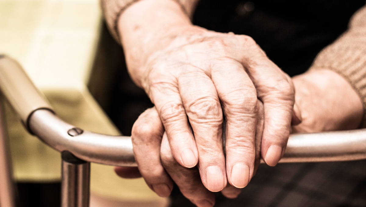 A photo of an elderly person's hands holding on to a walker.