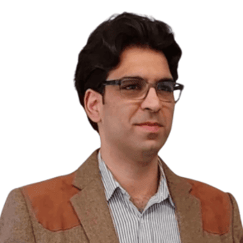 A man with glasses and a brown coat looks away from the camera.