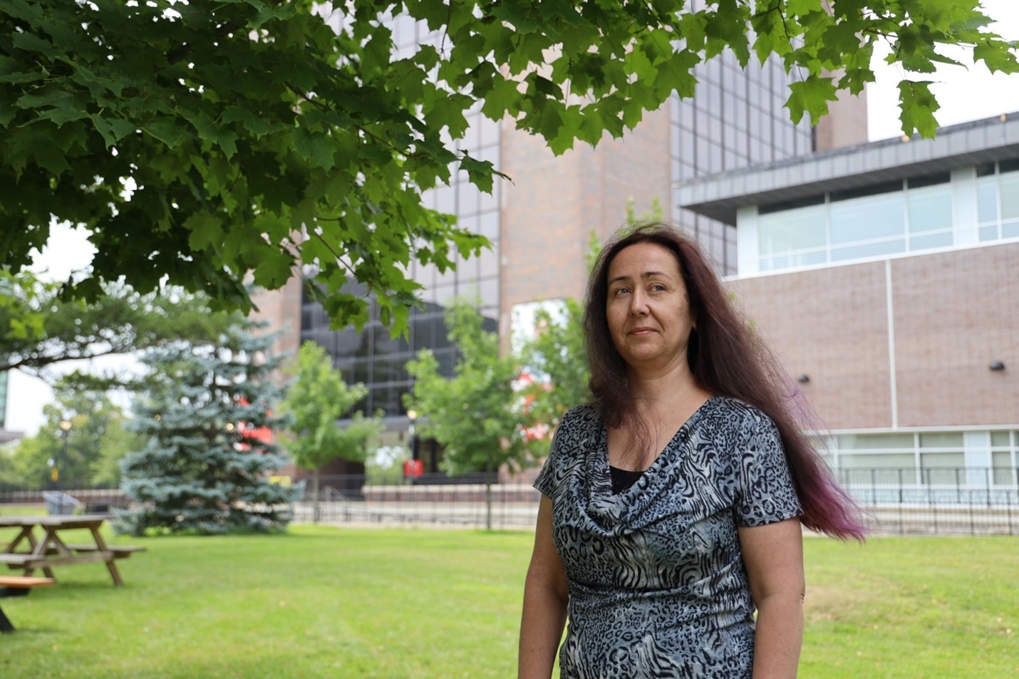 Kelly Lauzon stands in the quad in front of a Dunton Tower