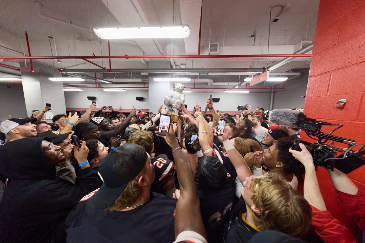 Ravens football players celebrate winning the 56th Panda Game with the Pedro the Panda Trophy.
