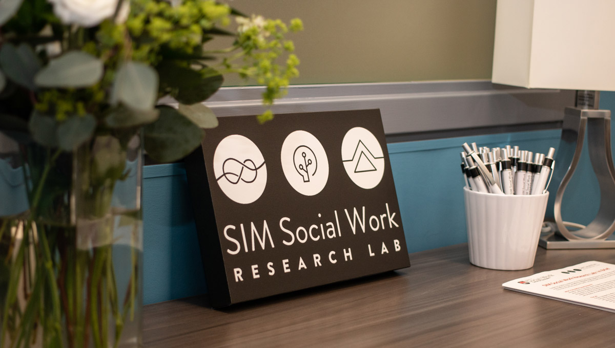 A SIM Lab sign sits on a desk next to a cup full of pens