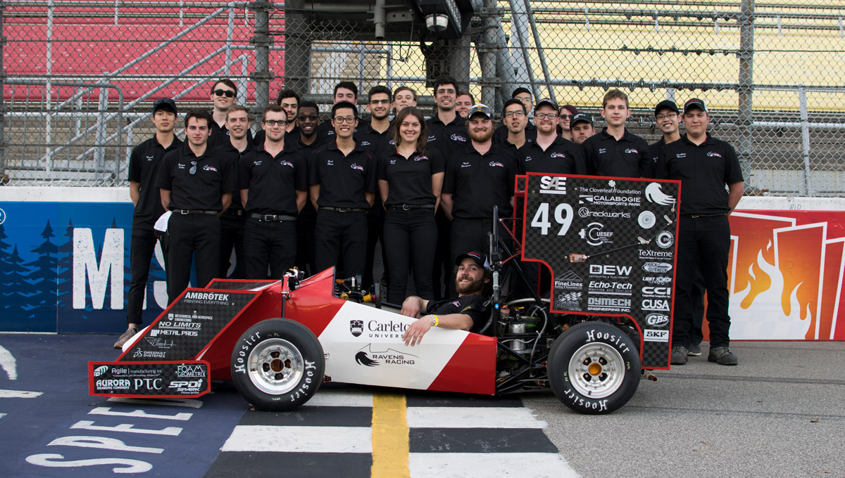 The Ravens Racing 2018 team poses together with their vehicle at a race track.