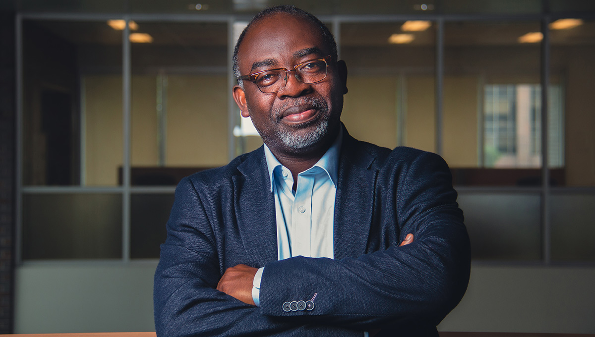 Adegboyega Ojo, the new Canada Research Chair in Governance and Artificial Intelligence, wearing a blue blazer and light blue dress shirt, crosses his arms while looking at the camera