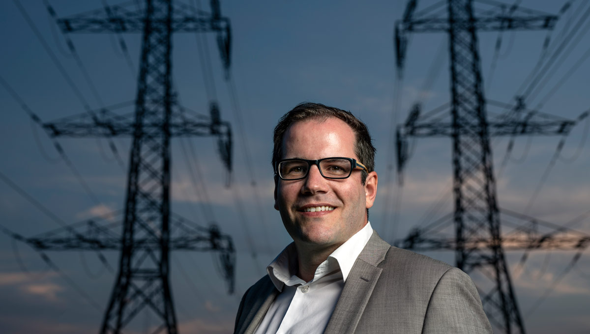 Alex Wilner stands in front of power lines on a clear evening. Prof. Alex Wilner and PhD candidate Casey Babb have been awarded a research grant for their project assessing threats to Canada's energy sector.