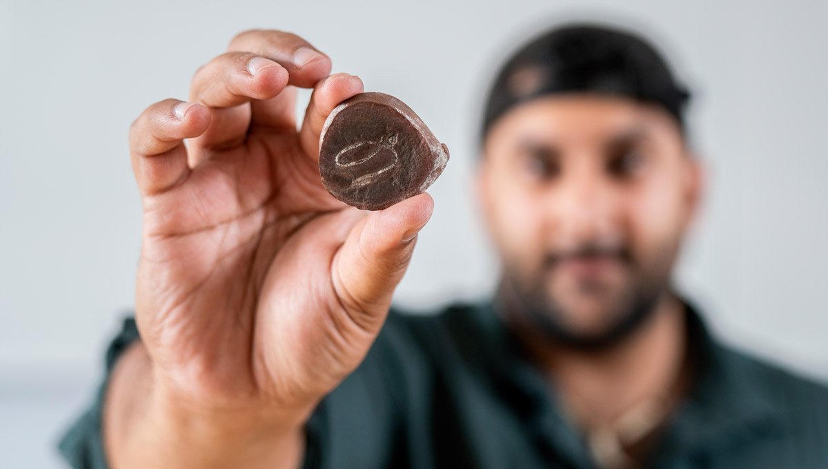 Arjan Mann holds a small rock containing a fossil.