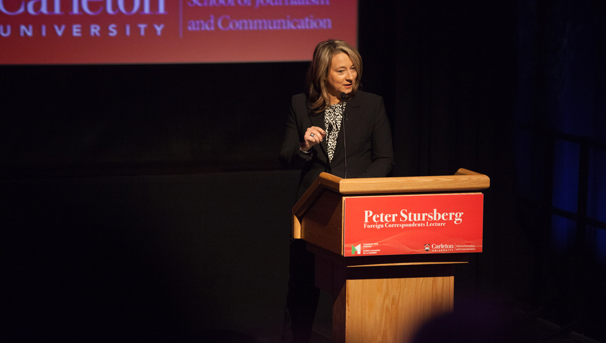 Adrienne Arsenault speaks at a podium emblazoned with the words Peter Stursberg Foreign Correspondents Lecture