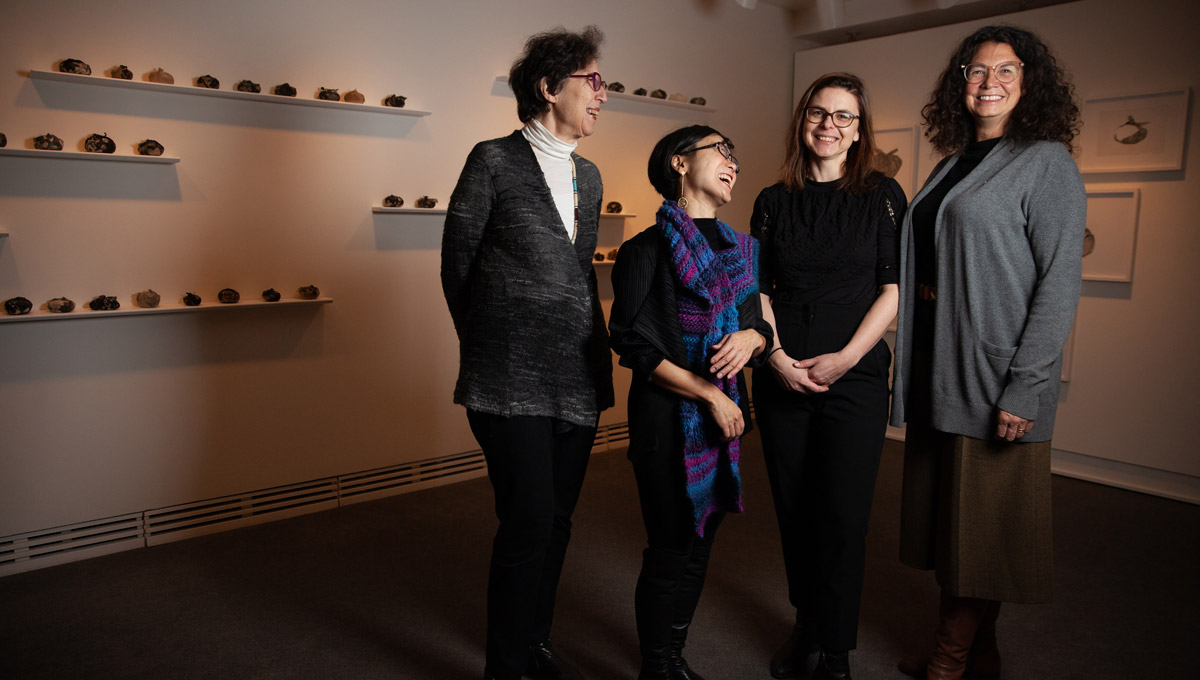 A group of women academics stand together laughing in the Carleton University Art Gallery.