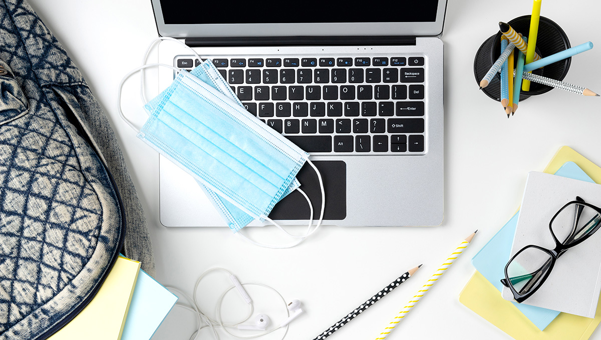 Modern laptop with backpack and stationery on white table