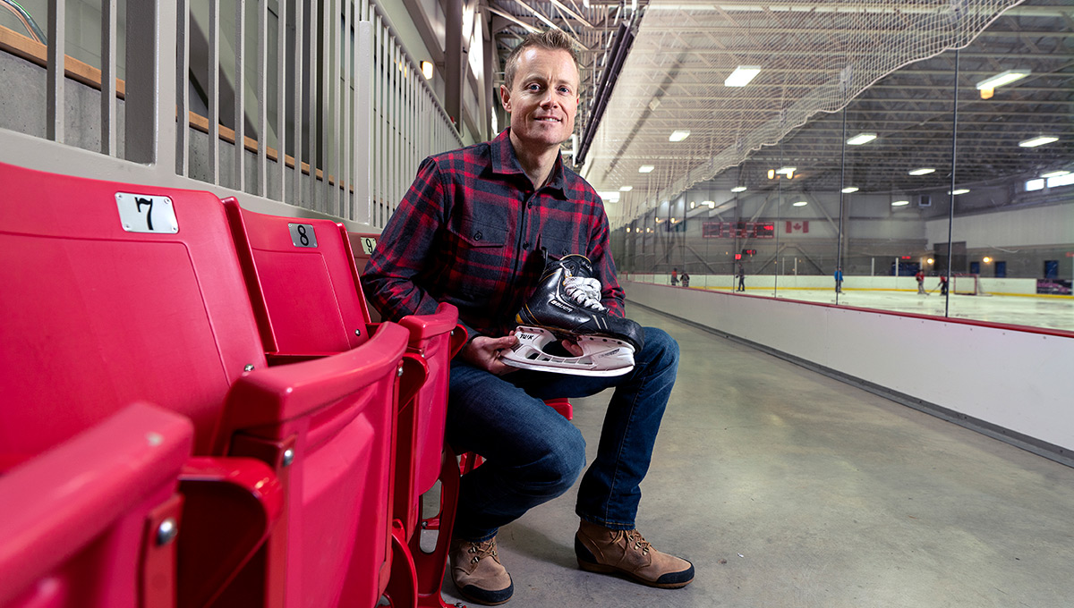 The photo features 'Blade Barber' Tim Maxwell sitting in a skating rink, holding a skate.