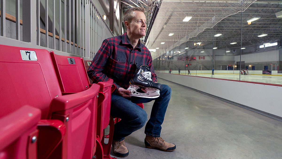 The photo features 'Blade Barber' Tim Maxwell sitting in a skating rink, holding a skate.