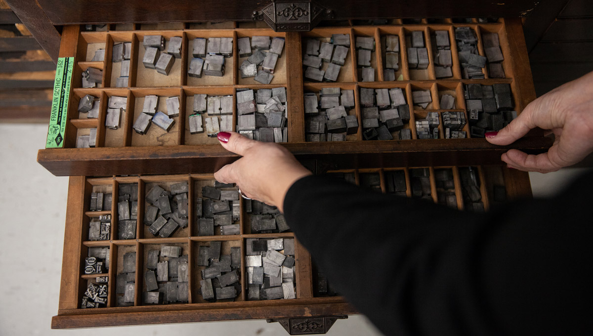 A top-down view of a drawer full of small iron printing press components.