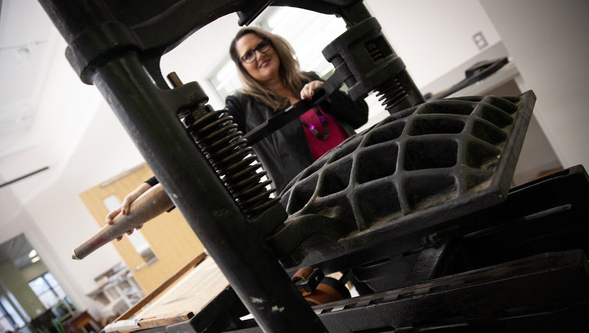 Patti Harper looks through the iron components of an antique printing press.
