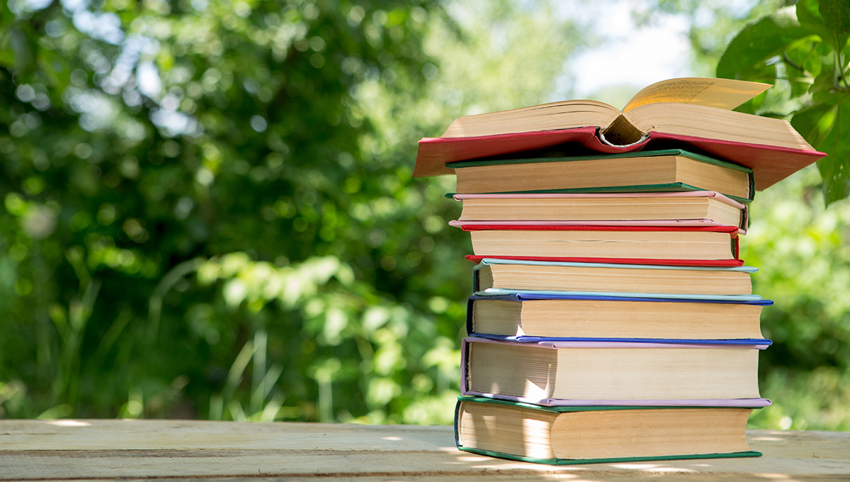 Open book on a wooden table in a garden, sunny summer day, reading in a vacation concept