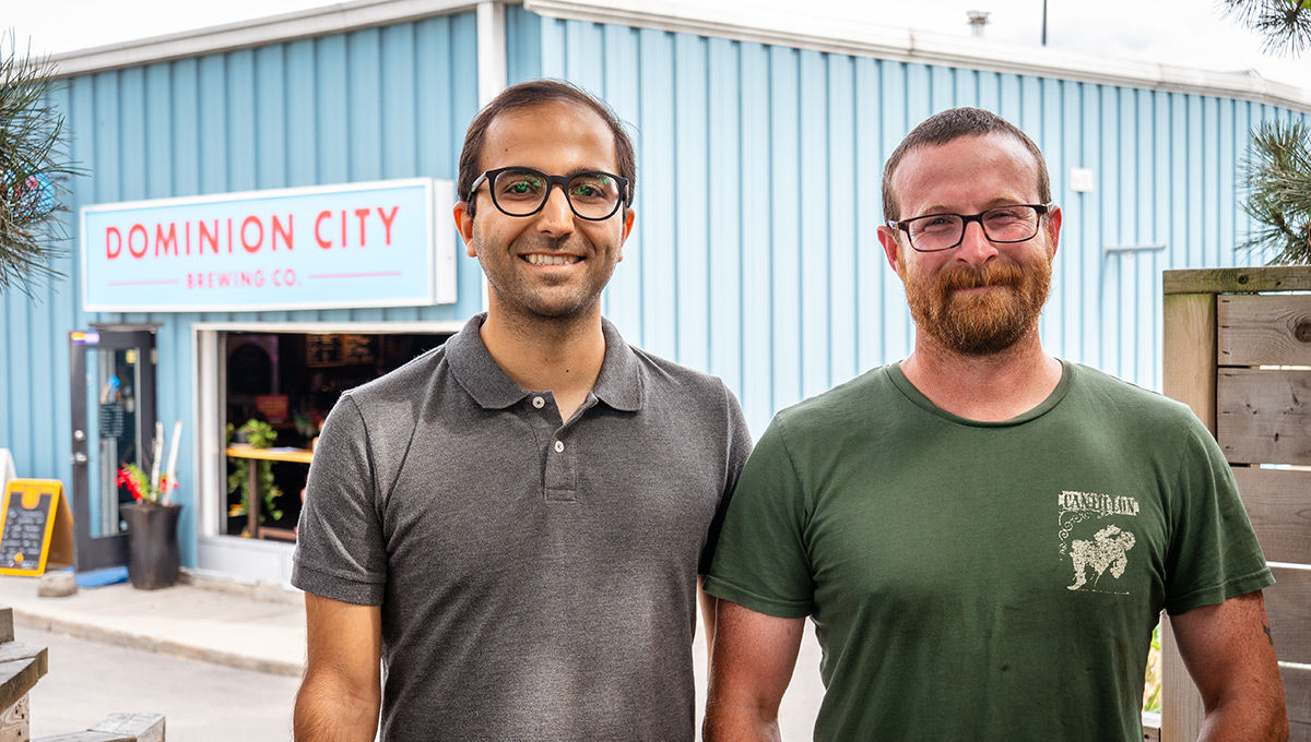 Two men posing for a photo in front of the Dominion City business.