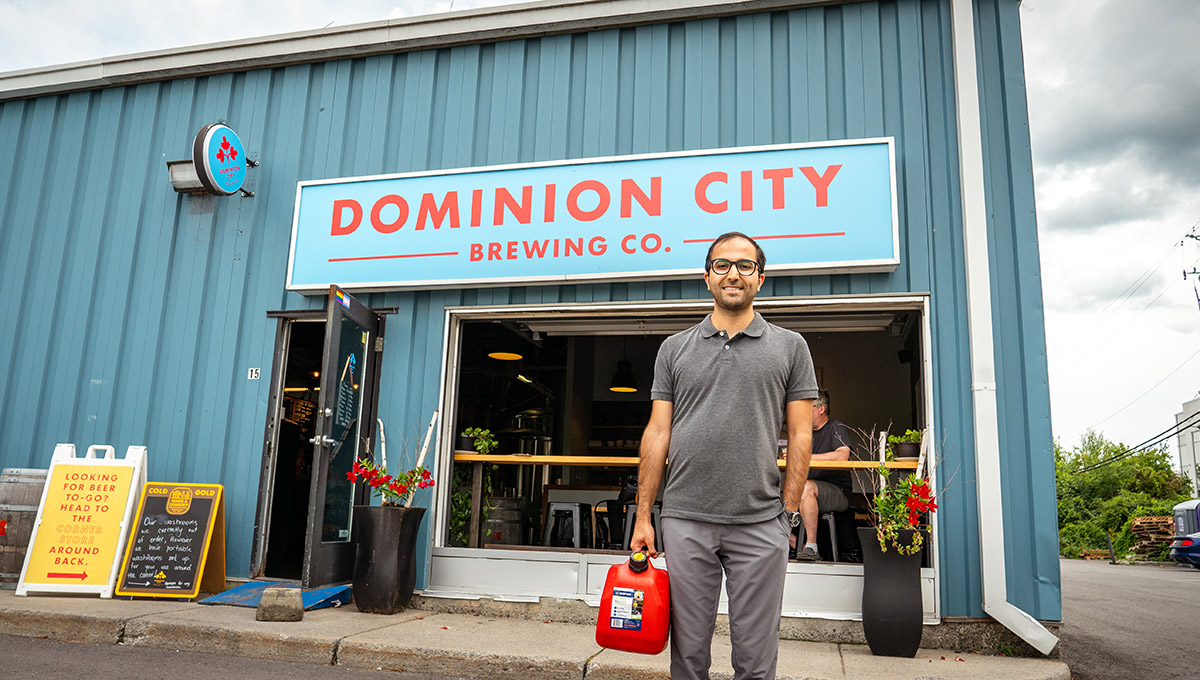 A man holding a gas tank stands in front of a business.