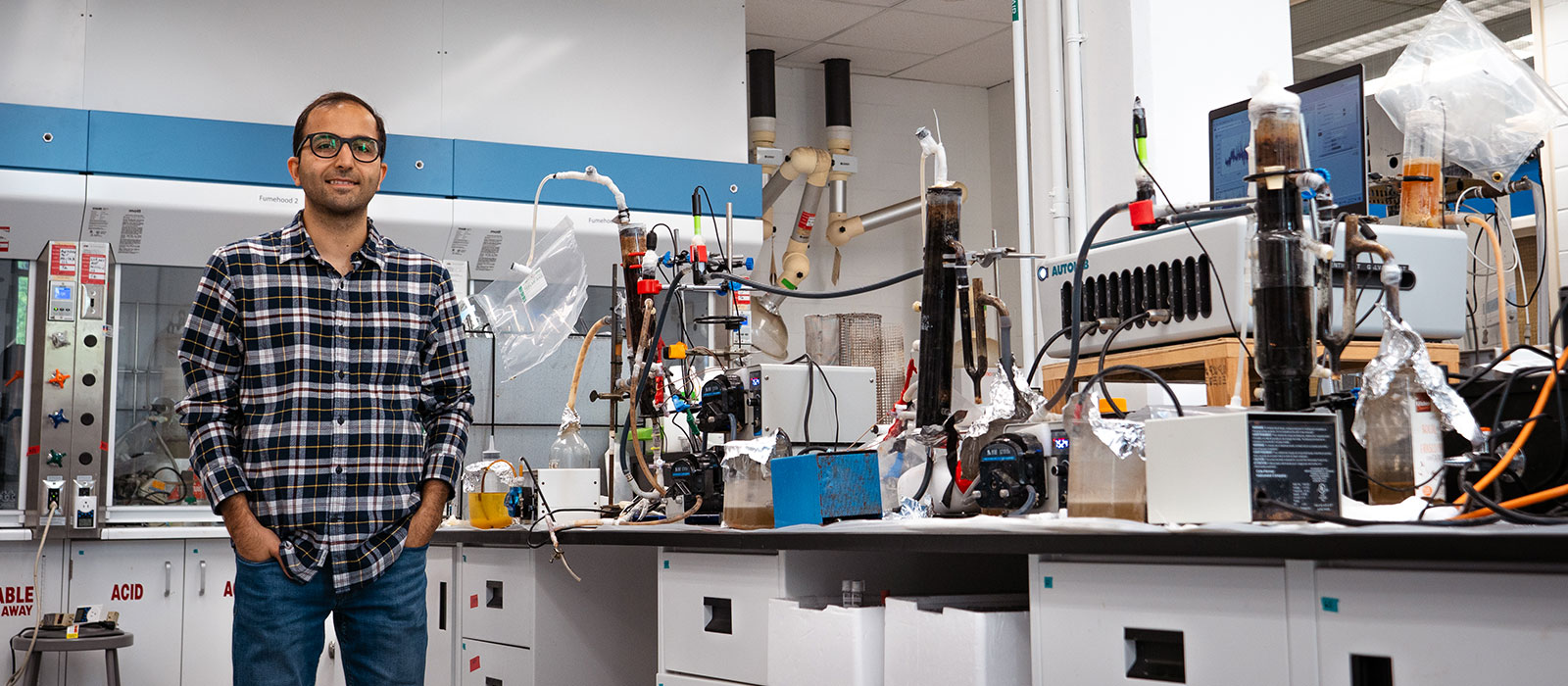 A man poses for a photo while standing next to lab equipment on a table.