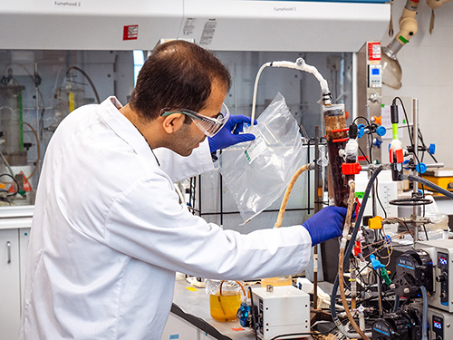 A man wearing a lab coat uses equipment in a lab.