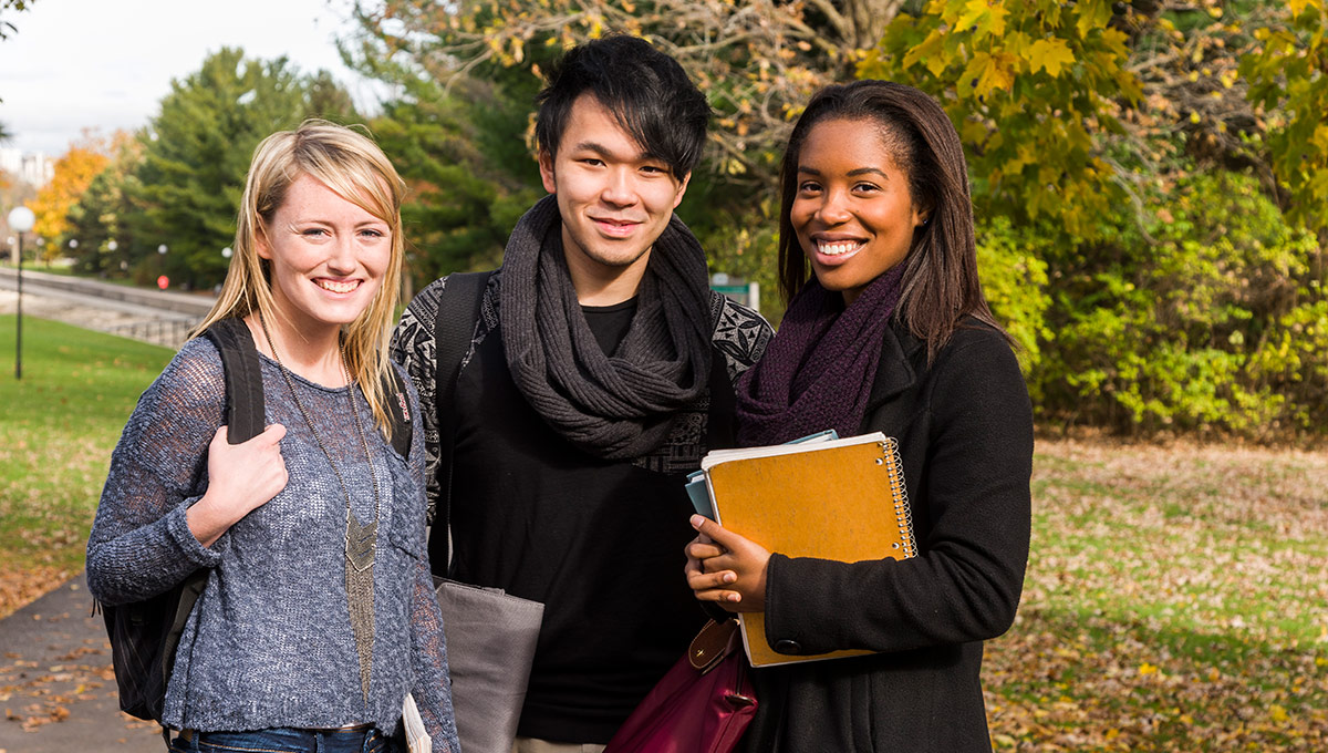 Carleton University students standing together on campus on a fall day.