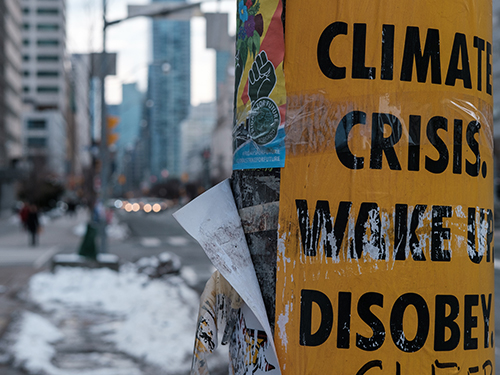 A climate change related poster on a pole on a street.