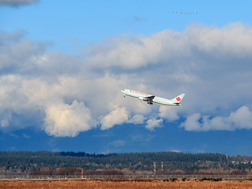 A distant view of an Air Canada flight taking off from an airport.