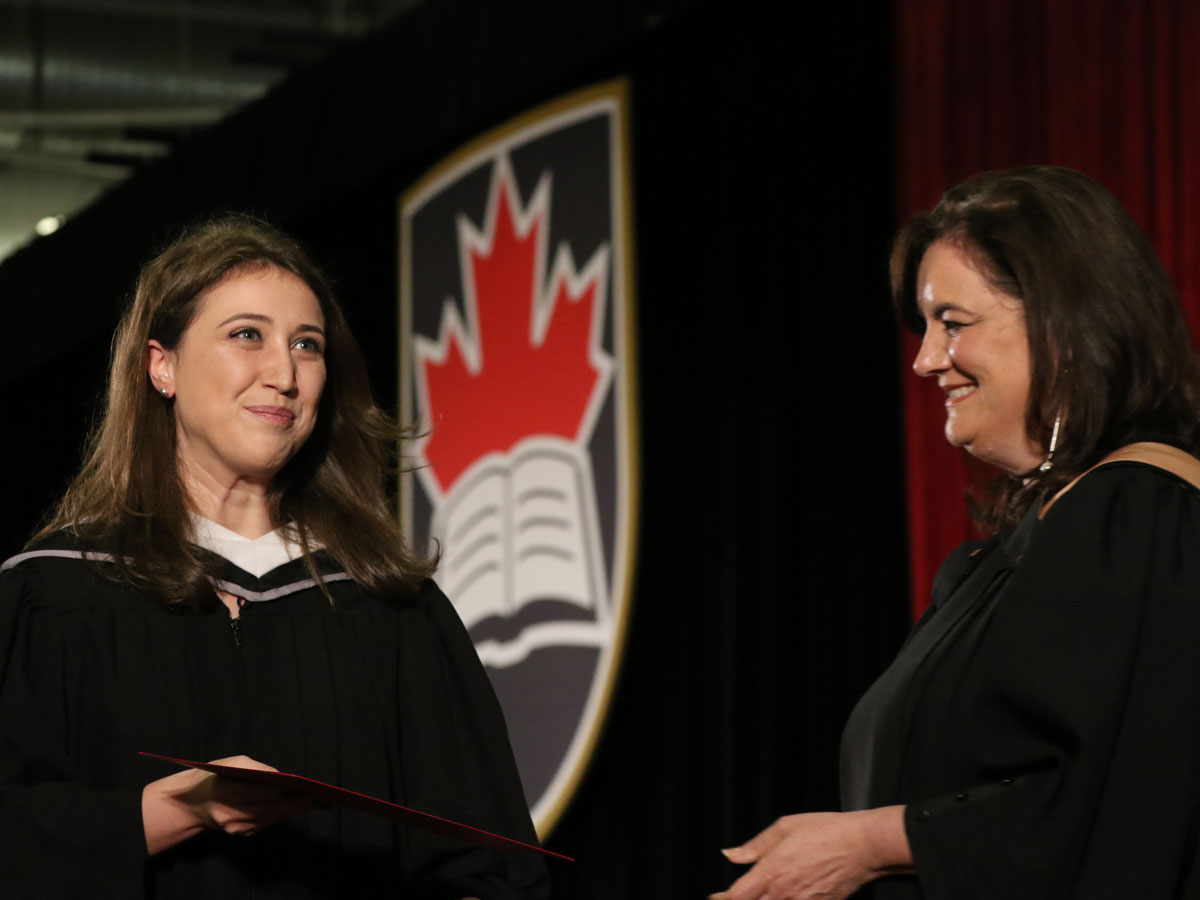 A graduating student receives her degree onstage.