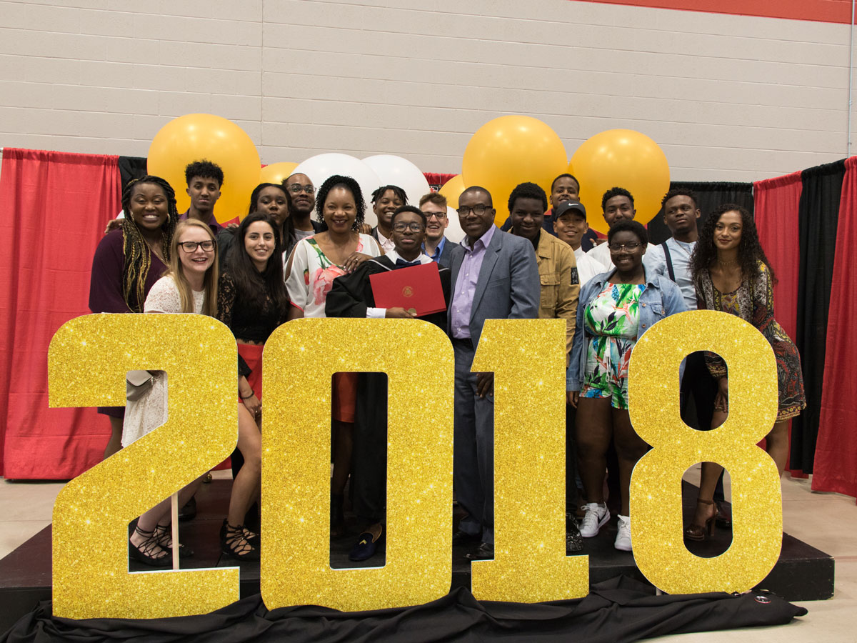 A group of students and their families gather around a large 2018 sign during Carleton University's Convocation.